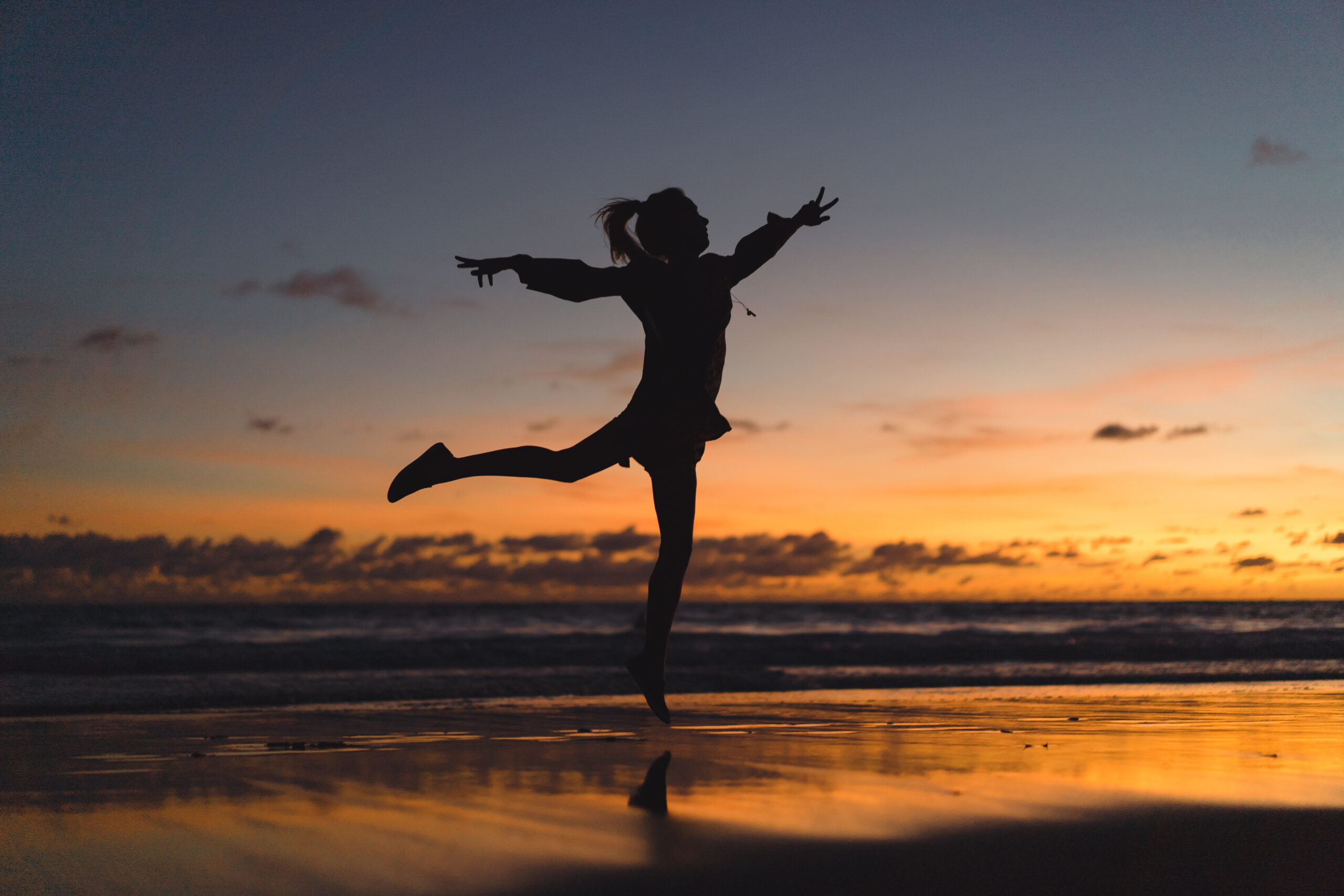 people on the beach at sunset. the girl is jumping against the b